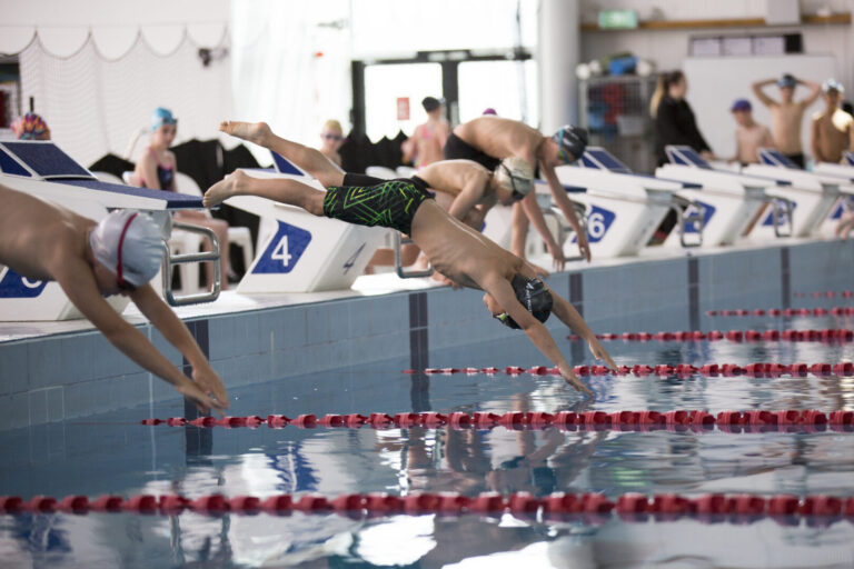 Children diving into a pool during a swimming sports event