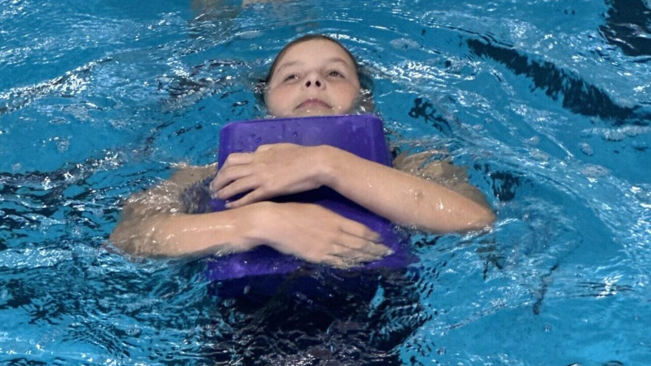 Water Safety girl floating on her back holding an object