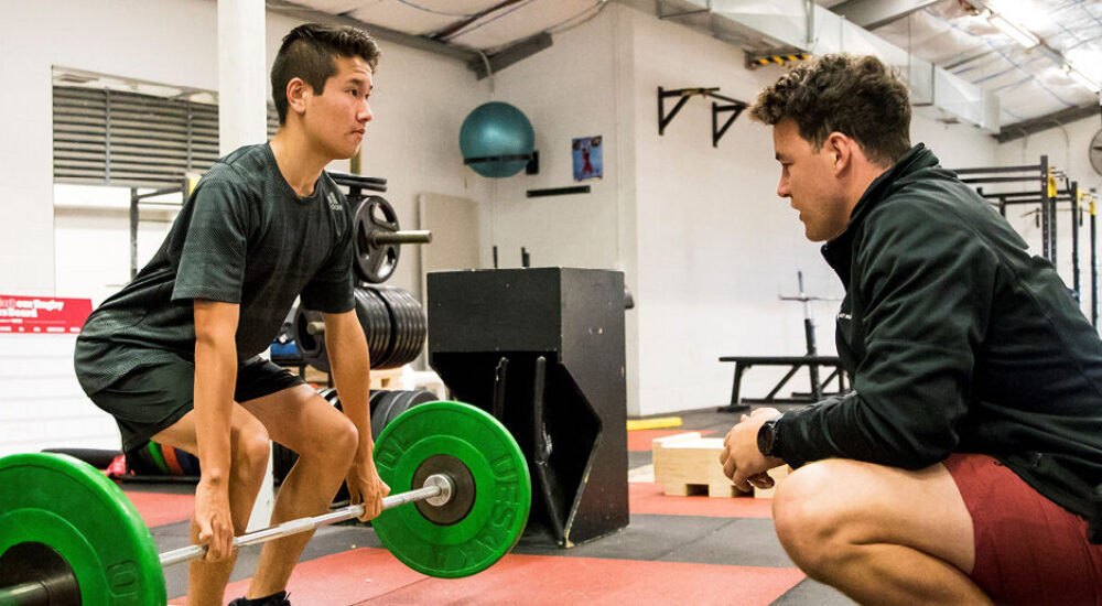 Coach giving tips to an athlete lifting