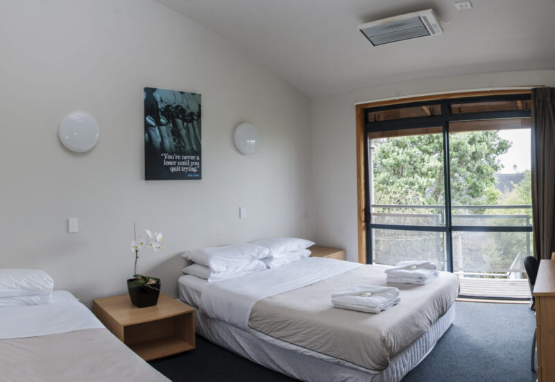 AUT Millennium Accommodation room with a double bed, single bed, amenities, desk and chair, chair, tv and tv cabinet