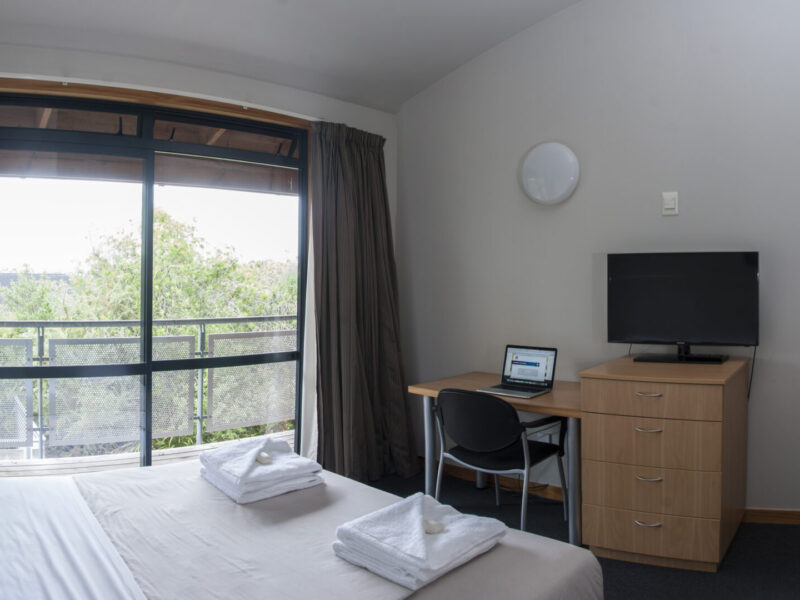 AUT Millennium Accommodation room with a double bed, amenities, desk and chair, tv and tv cabinet