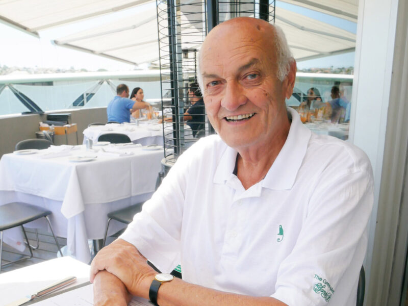 Sir Owen Glenn at a restaurant table, smiling at the camera