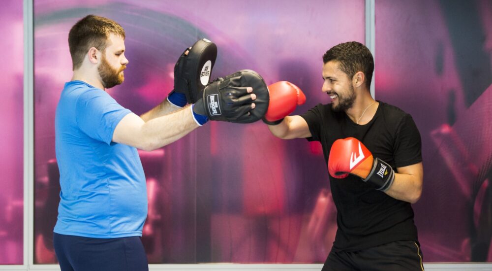 Two gym members are paired up for sparring in a Boxfit class