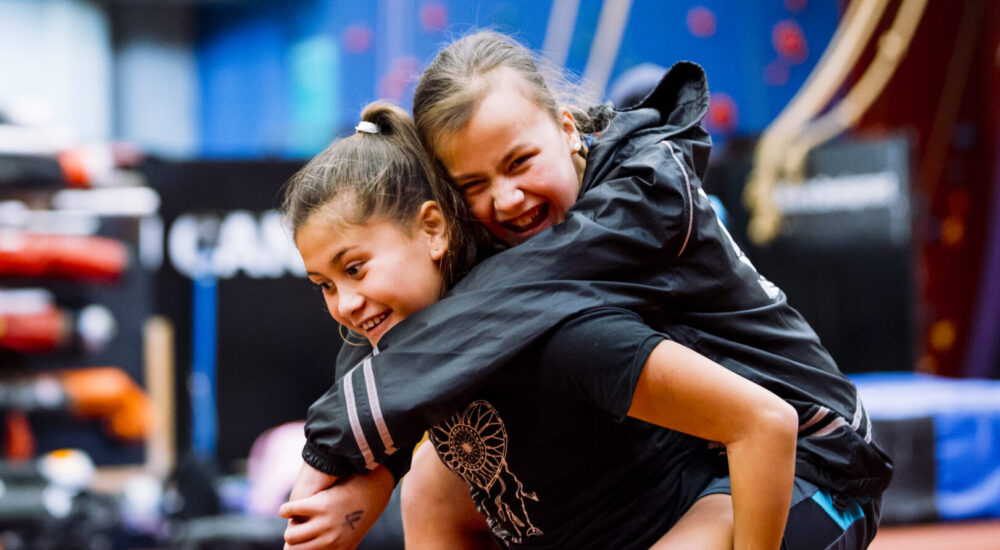 Two children laughing as one child gives the other a piggy back ride