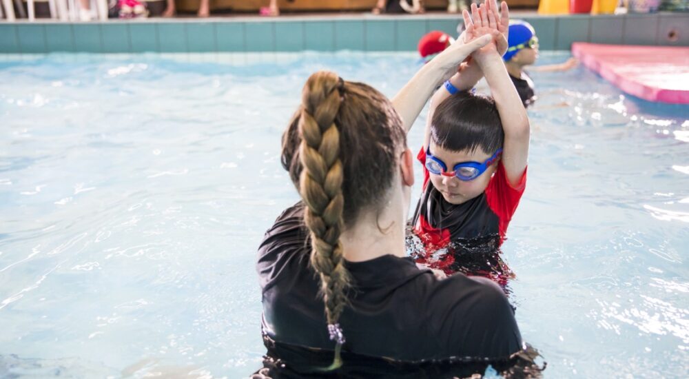 A Swim School teacher correcting the streamline position of a child in her swim class