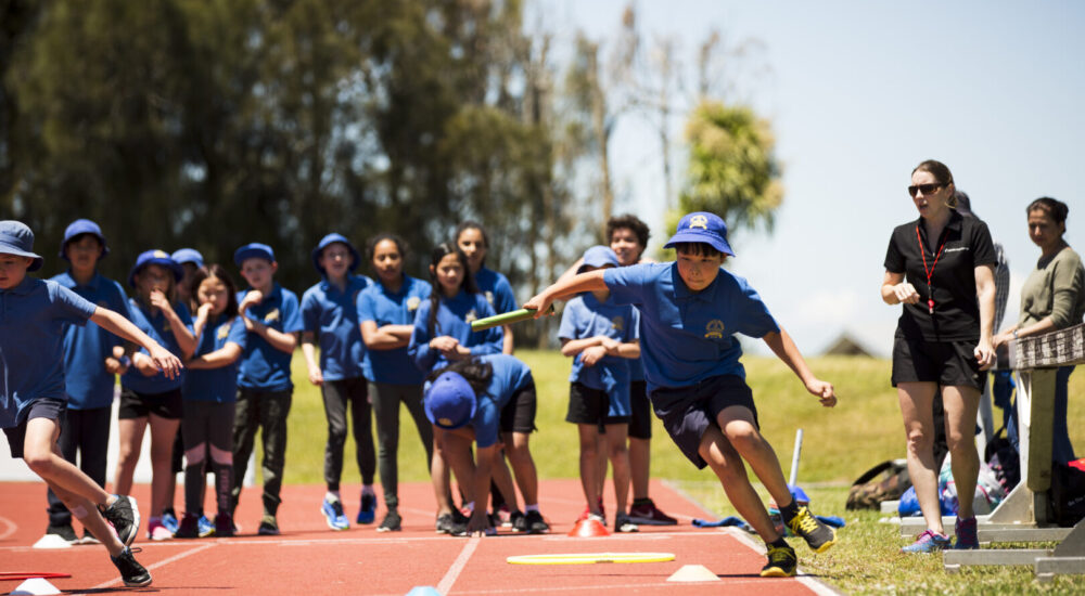Two children participating in a zig-zag relay while their instructor and mates encourage them