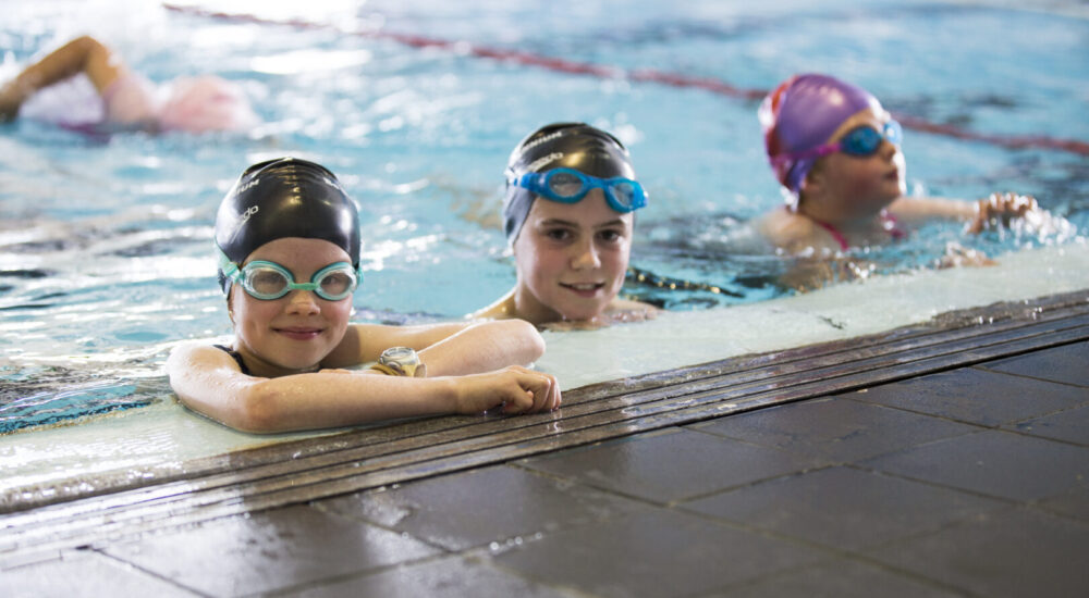 Three children in the pool, waiting on the side