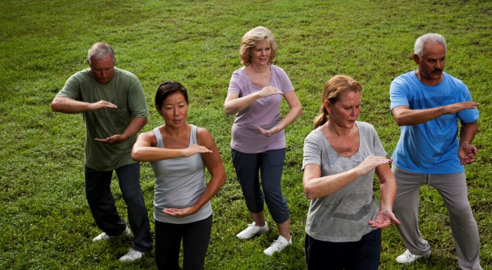 Adults practising Tai Chi in the park.